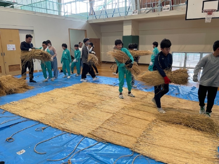 ネブタ本体に詰める藁を運ぶ児童たち