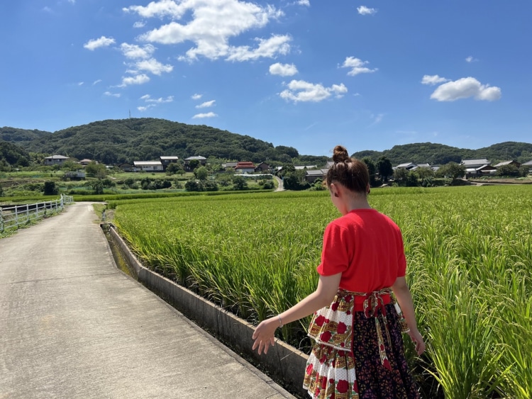 田んぼ道を女性がのんびり散歩している