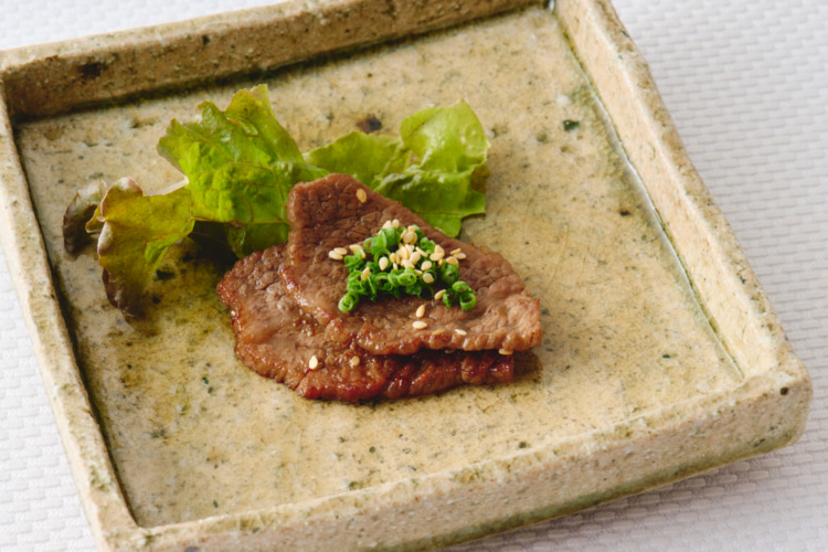 ゴマと青ネギが添えられた焼き肉