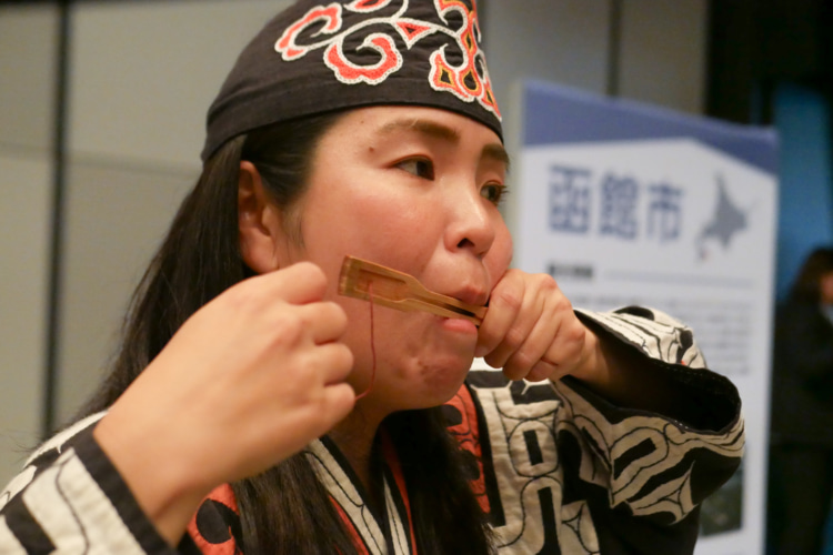 アイヌの民族衣装を着て伝統楽器ムックリを演奏する女性