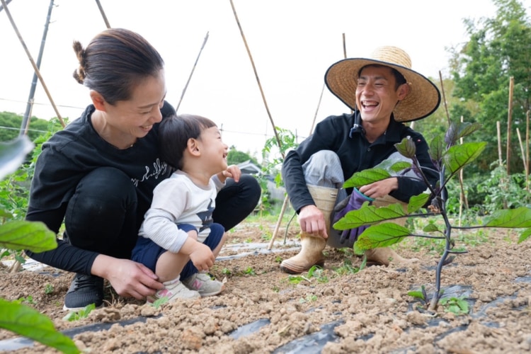 幼い子どもと笑顔の女性と農作業をする笑顔の男性