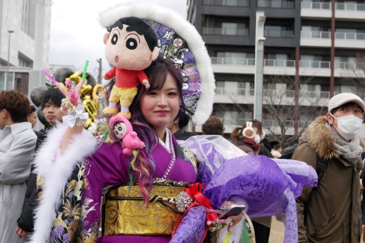 頭にクレヨンしんちゃんのぬいぐるみをのせた新成人