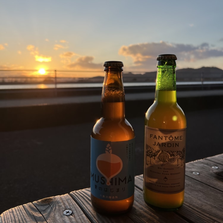 夕日を背景にビンのクラフトビールがテーブルの上に並んでいる