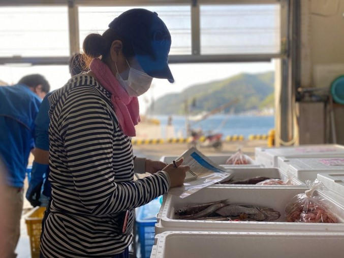 市場で魚を見ている女性