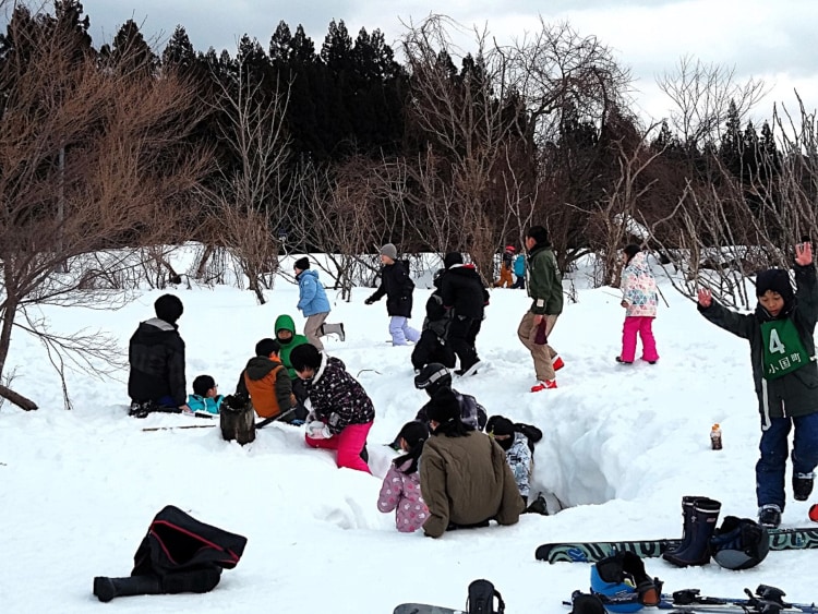 たくさんの子どもが入り混じって雪で遊んでいる