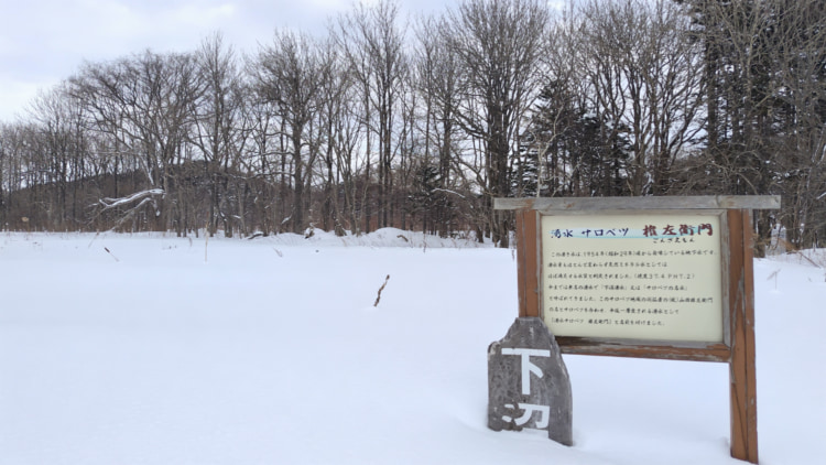 雪の中に立つ湧き水の看板