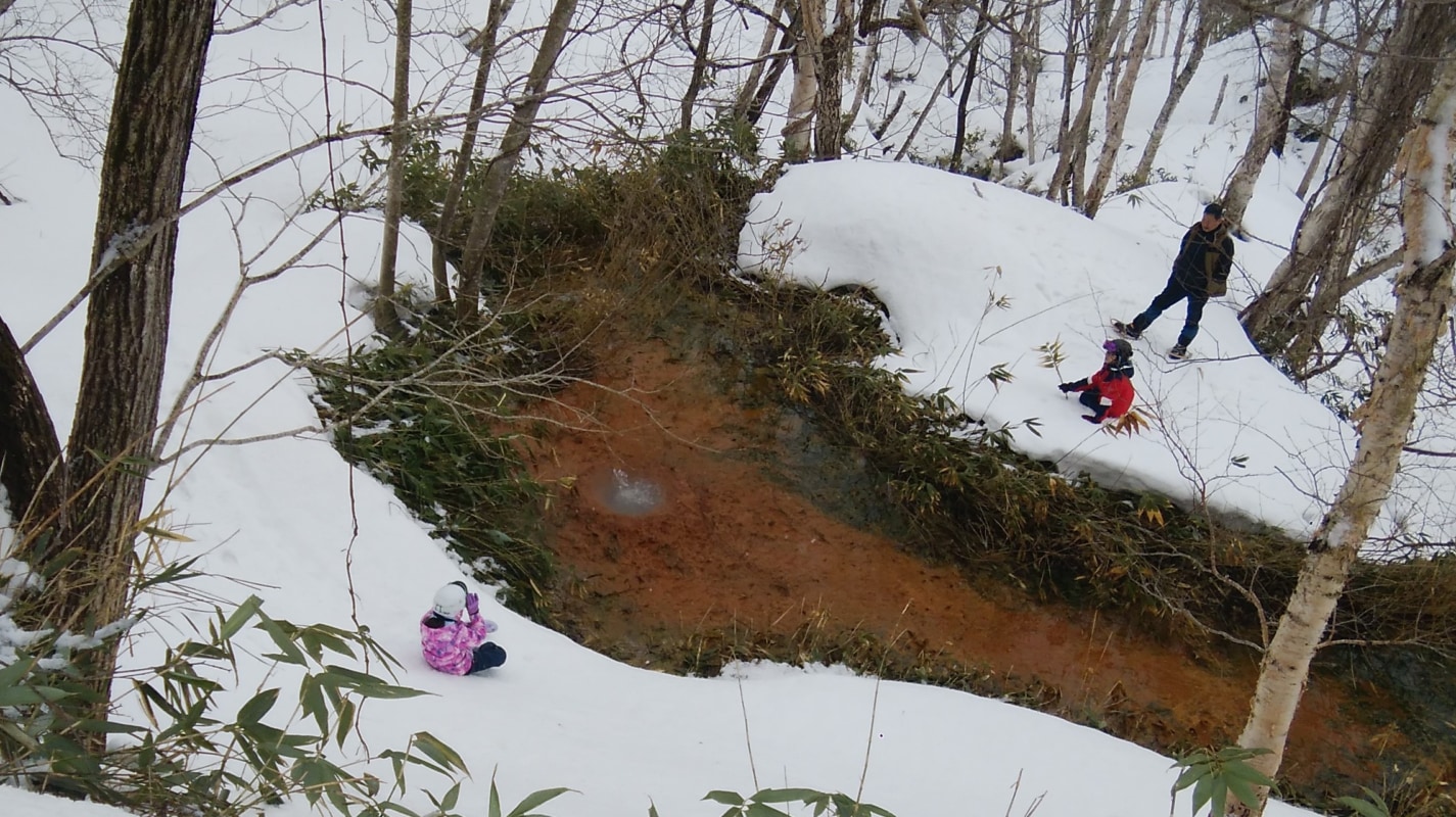 雪山で遊ぶ男性と２人の子ども
