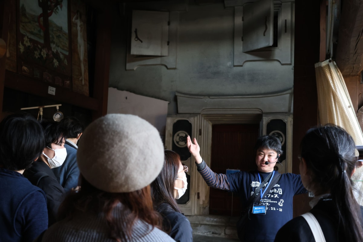 建物内で説明をする男性を聞く人々